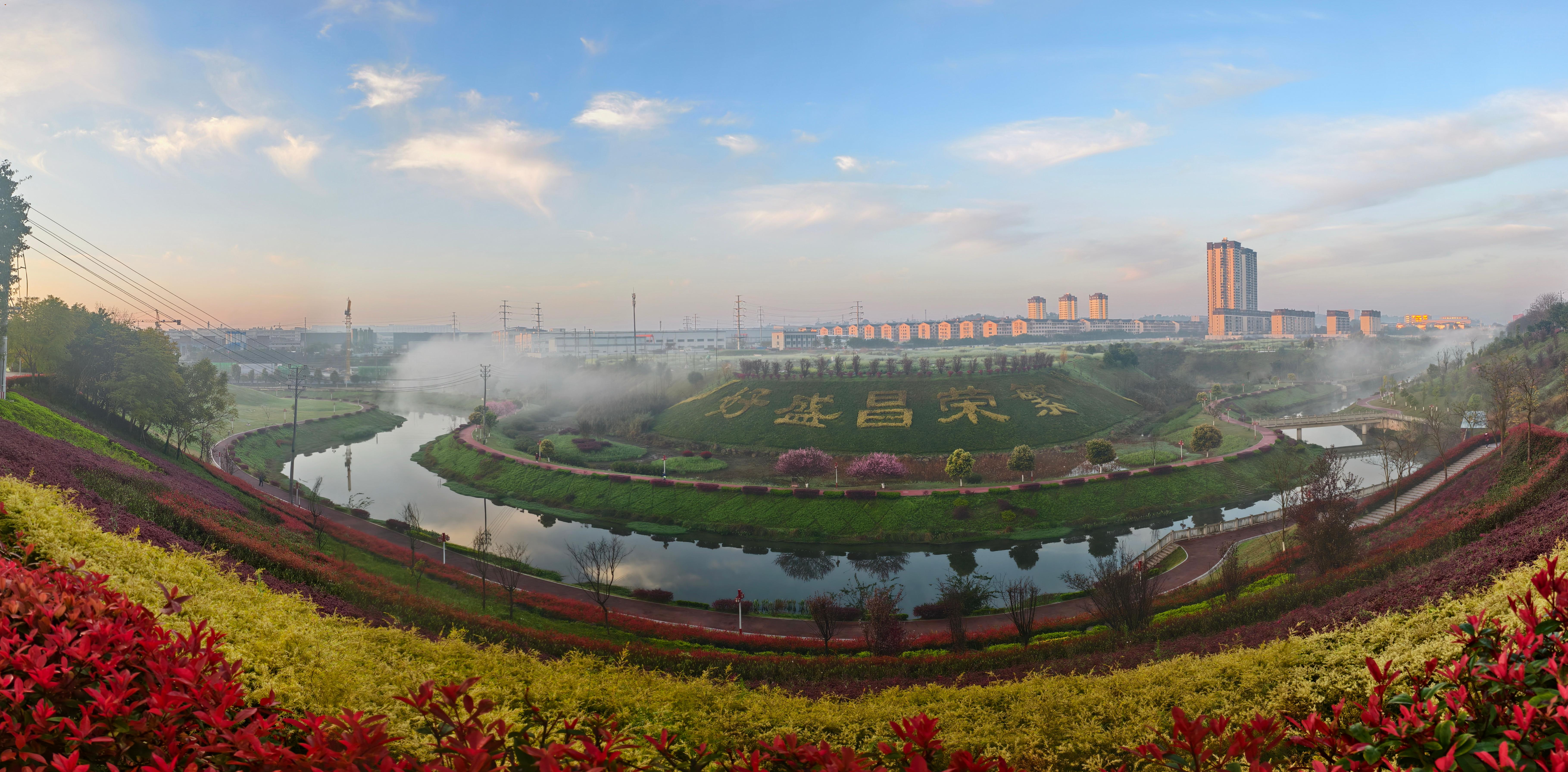 《七彩广场》2026年3月10日，拍于七彩广场。早上7点过，天空晴朗，有晨雾，各种植物颜色正艳，体现七彩广场特色。用手机全景模式拍成片。李建友  13509427836.jpg